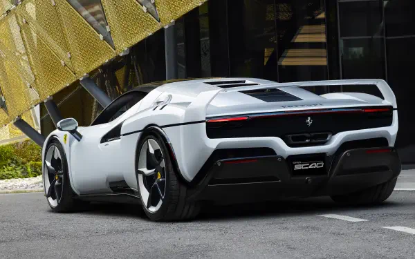 White Ferrari SC40 vehicle shown rear three-quarter, parked by modern architecture - 2K Quad HD PC desktop wallpaper/background.