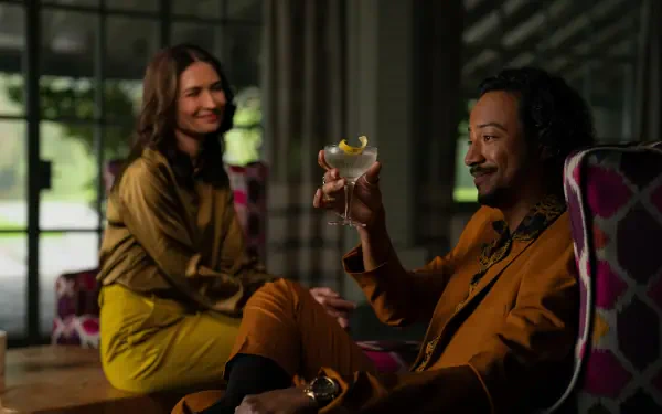 Two characters from TV show Pluribus share drinks in a stylish lounge; warm tones and sharp detail — 5K Ultra HD PC desktop wallpaper/background.