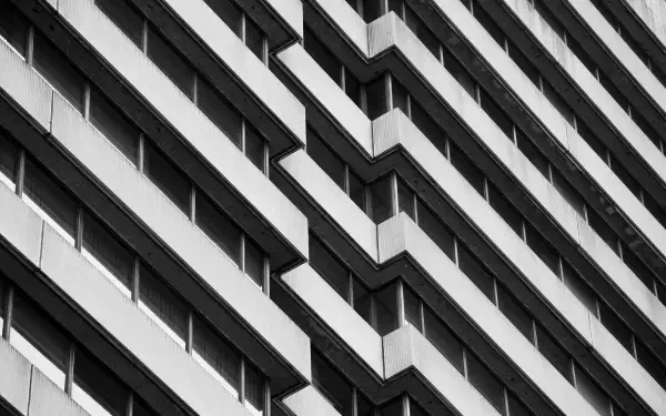 Monochrome Brutalist building facade with repeating angular balconies in strong diagonal perspective — HD PC desktop wallpaper and background.