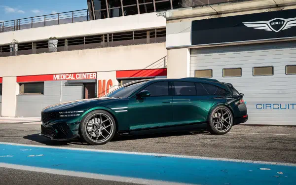 Side view of a teal Genesis G90 parked on a racetrack in bright sunlight — 2K Quad HD PC desktop wallpaper/background.