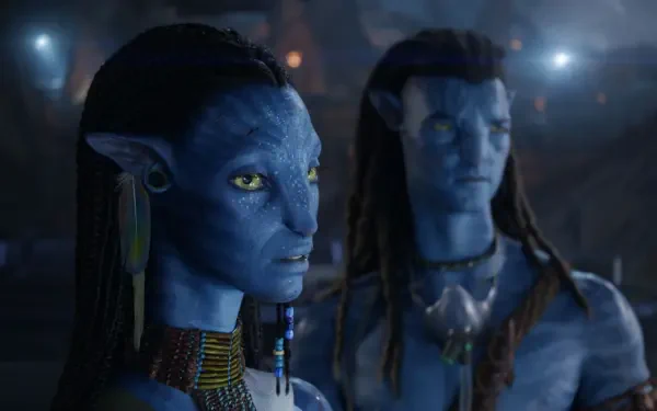 HD PC desktop wallpaper and background from the movie Avatar: Fire and Ash showing two blue-skinned Na'vi: a focused female with braided hair and jewelry, and a blurred male behind her.