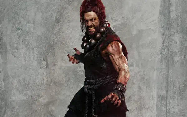 Street Fighter (2026) 2K Quad HD PC desktop wallpaper/background: fierce, blood-smeared martial artist wearing prayer beads and a torn gi, posed against a textured gray wall.