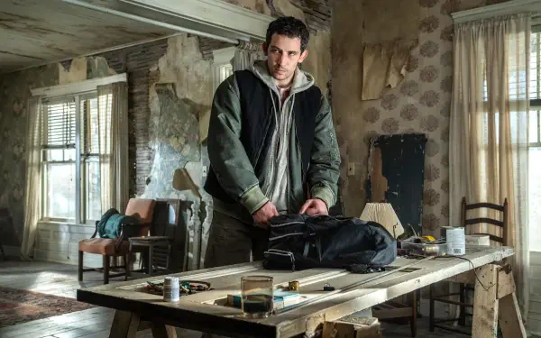 Brooding man in a dilapidated room leans over a cluttered table — cinematic still from the movie Disclosure Day, rendered as a 5K Ultra HD PC desktop wallpaper.