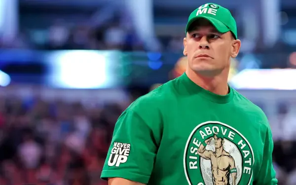 HD desktop wallpaper of a muscular man in a green cap and Rise Above Hate shirt, standing in a packed arena with bright lights and a blurred cheering crowd behind him.
