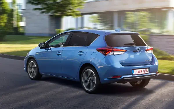 HD PC desktop wallpaper: blue Toyota Auris hatchback driving along a sunlit street, car shown from a rear three-quarter view.