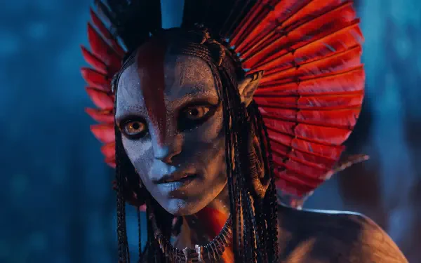 Avatar: Fire and Ash — close-up of a blue-skinned Na'vi with a red feathered headdress and glowing amber eyes, cinematic 4K Ultra HD PC desktop wallpaper/background.