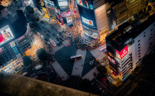 8K Ultra HD PC desktop wallpaper: aerial night cityscape of Shibuya Crossing in Tokyo, Japan — neon billboards, busy crosswalks and glowing streets.