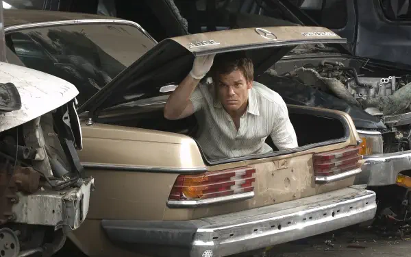 Man emerging from a car trunk in a junkyard; 2K Quad HD PC desktop wallpaper. Tagged: TV show, Dexter. I don't know the person's identity.