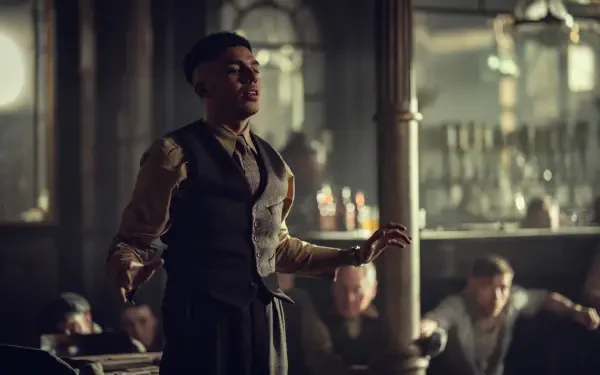 8K Ultra HD PC wallpaper: actor from Peaky Blinders: The Immortal Man in a period vest stands in a dim, smoky pub, striking a dramatic pose.