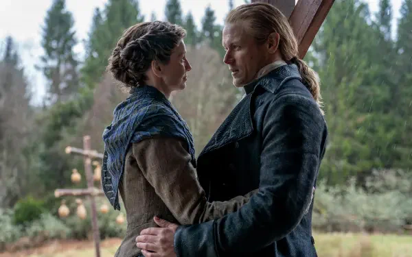 Outlander TV show scene: two actors embrace outdoors — a woman in a shawl and a man in a dark coat, HD PC desktop wallpaper/background.