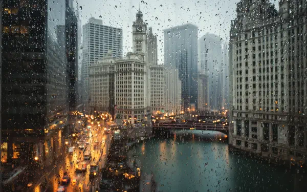 Rain-spattered Chicago cityscape on the Chicago River with the Wrigley Building and glowing streetlights — moody 2K Quad HD PC desktop wallpaper, Illinois.
