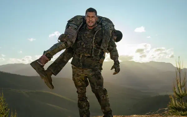 War Machine (2026) 4K Ultra HD PC desktop wallpaper: armored soldier carries a wounded comrade across a sunlit mountain ridgeline at dusk.