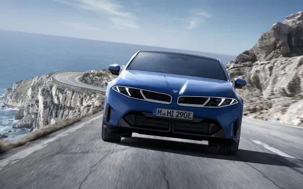 Blue BMW i3 electric vehicle front view driving on a coastal road, rendered as 4K Ultra HD PC desktop wallpaper background.