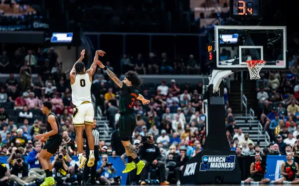 HD PC desktop wallpaper/background of NCAA action: Purdue Boilermakers player releasing a jump shot over defenders in a packed arena.