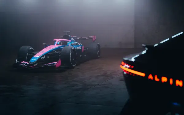4K Ultra HD desktop wallpaper: Alpine F1 Team race car in blue and pink livery parked in a dim garage, with a glowing ALPINE taillight in the foreground.