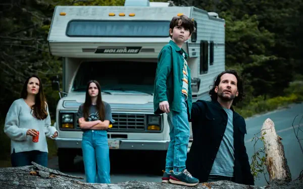 TV show From (2022) 5K Ultra HD PC desktop wallpaper: tense family of four — two adults and two youths — stand before a parked RV on a forest road under an overcast sky, wary expressions.