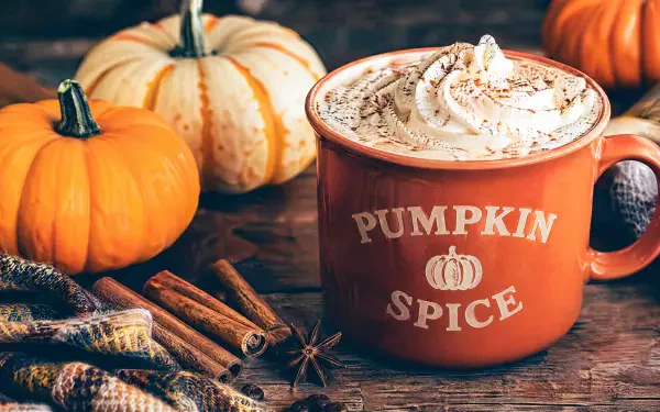 4K Ultra HD PC desktop wallpaper: pumpkin spice mug topped with whipped cream, surrounded by small pumpkins, cinnamon sticks and star anise on a rustic wooden table.