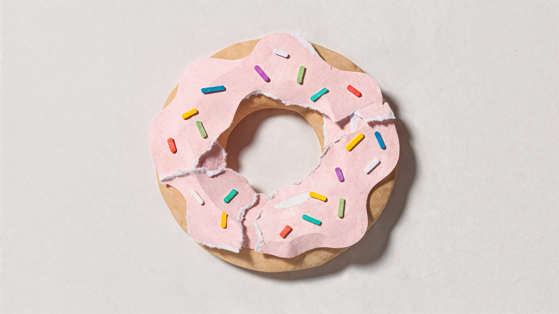 4K Ultra HD PC desktop wallpaper showing a pink-frosted doughnut with rainbow sprinkles on a pale background.