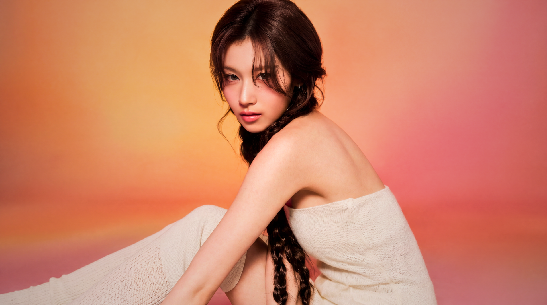 5K Ultra HD PC wallpaper: portrait of a young woman with long braided hair wrapped in a towel against a warm orange-pink gradient, styled with soft k-pop idol glam.