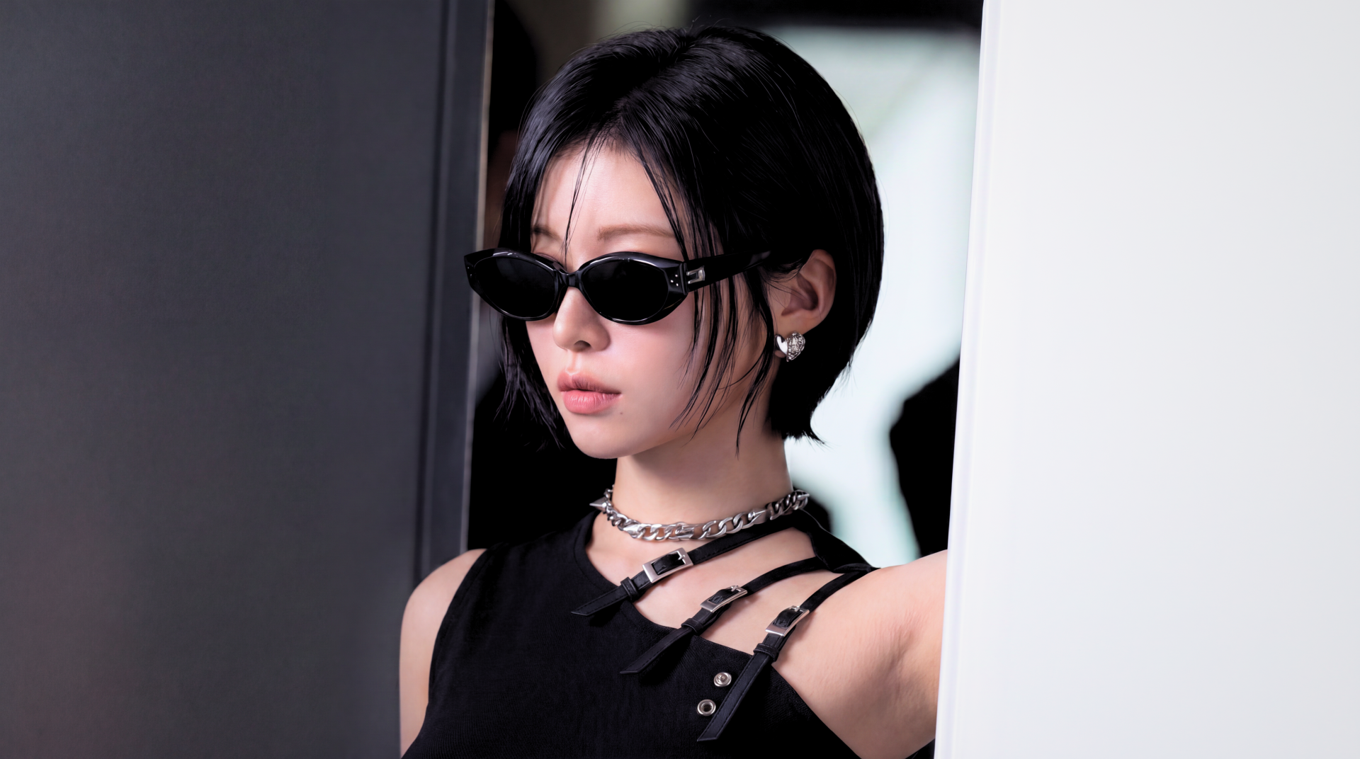 5K Ultra HD wallpaper: k-pop idol–styled Japanese model in sleek black The Matrix–inspired outfit with narrow sunglasses, cool moody studio background.