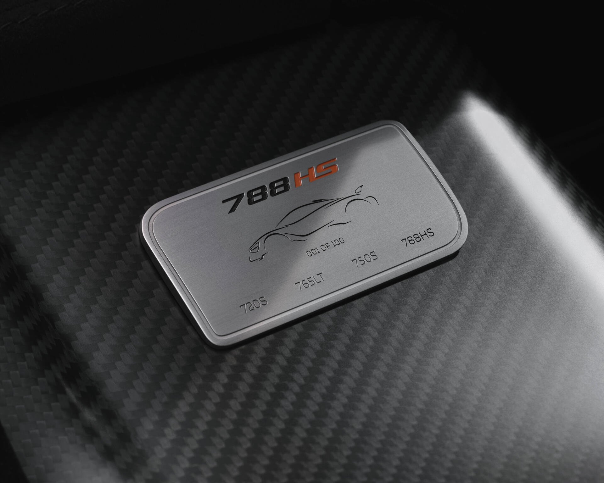 Close-up of a McLaren 788HS badge on carbon-fiber hood, vehicle detail rendered as an 8K Ultra HD PC desktop wallpaper/background.