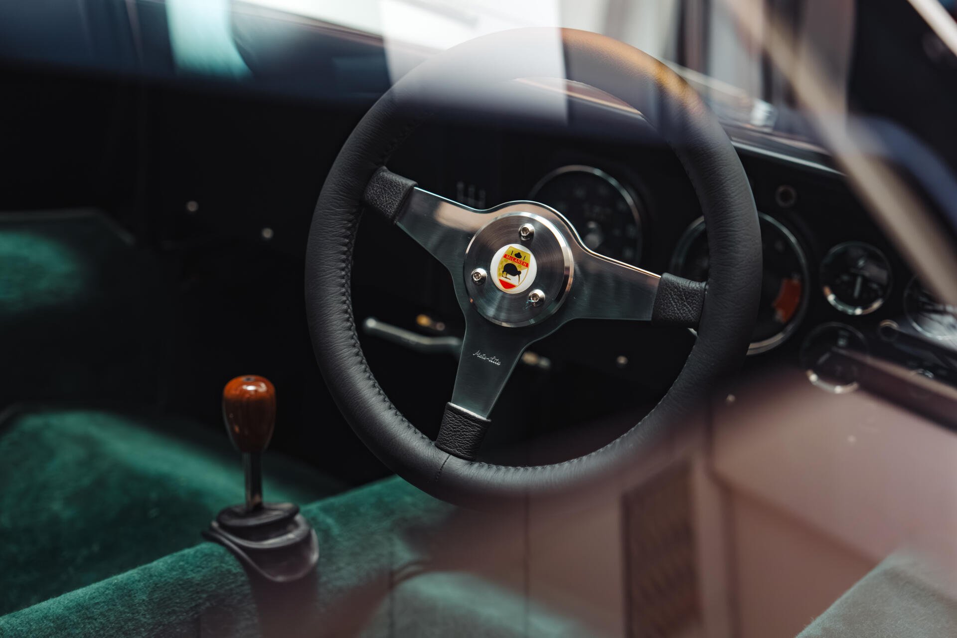8K Ultra HD PC desktop wallpaper of a McLaren G6GT vehicle interior; close-up of the steering wheel, dashboard gauges and manual gear shifter.