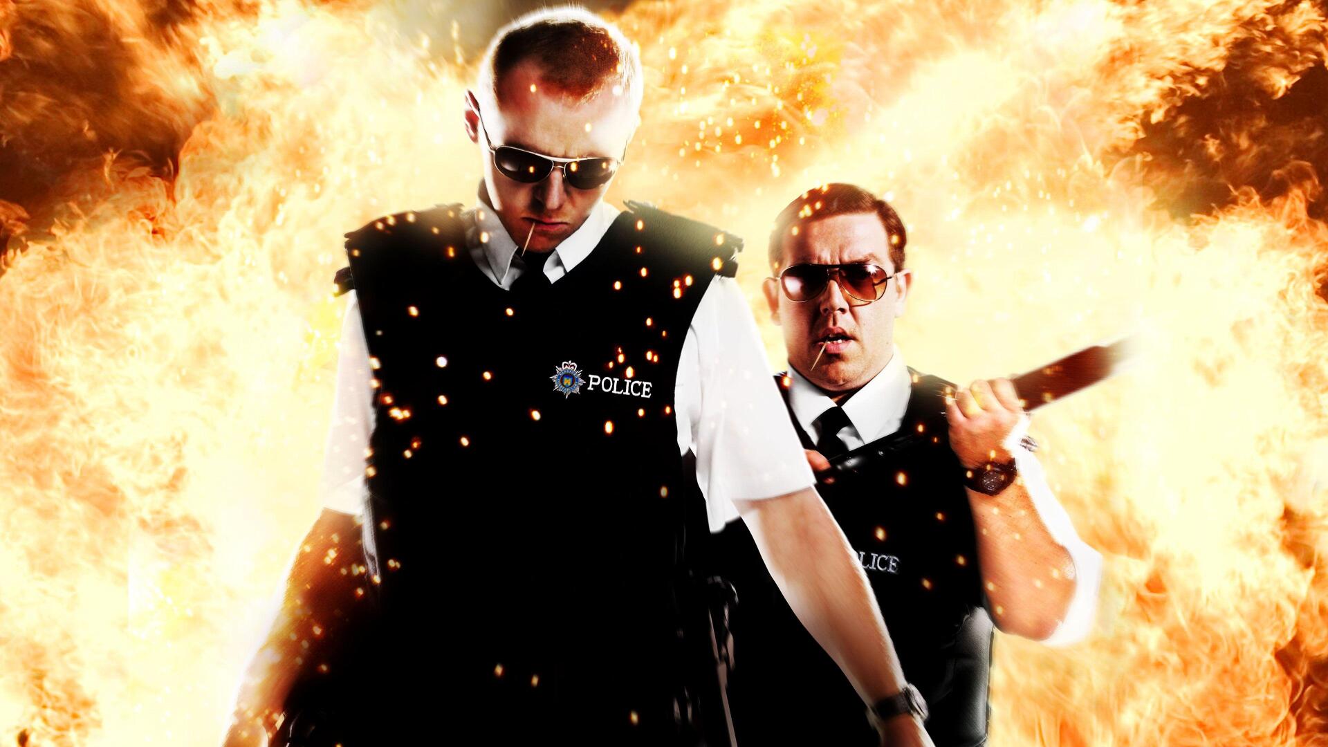 Hot Fuzz 4K Ultra HD PC wallpaper: two uniformed police officers in vests stride forward as a fiery explosion erupts behind them.