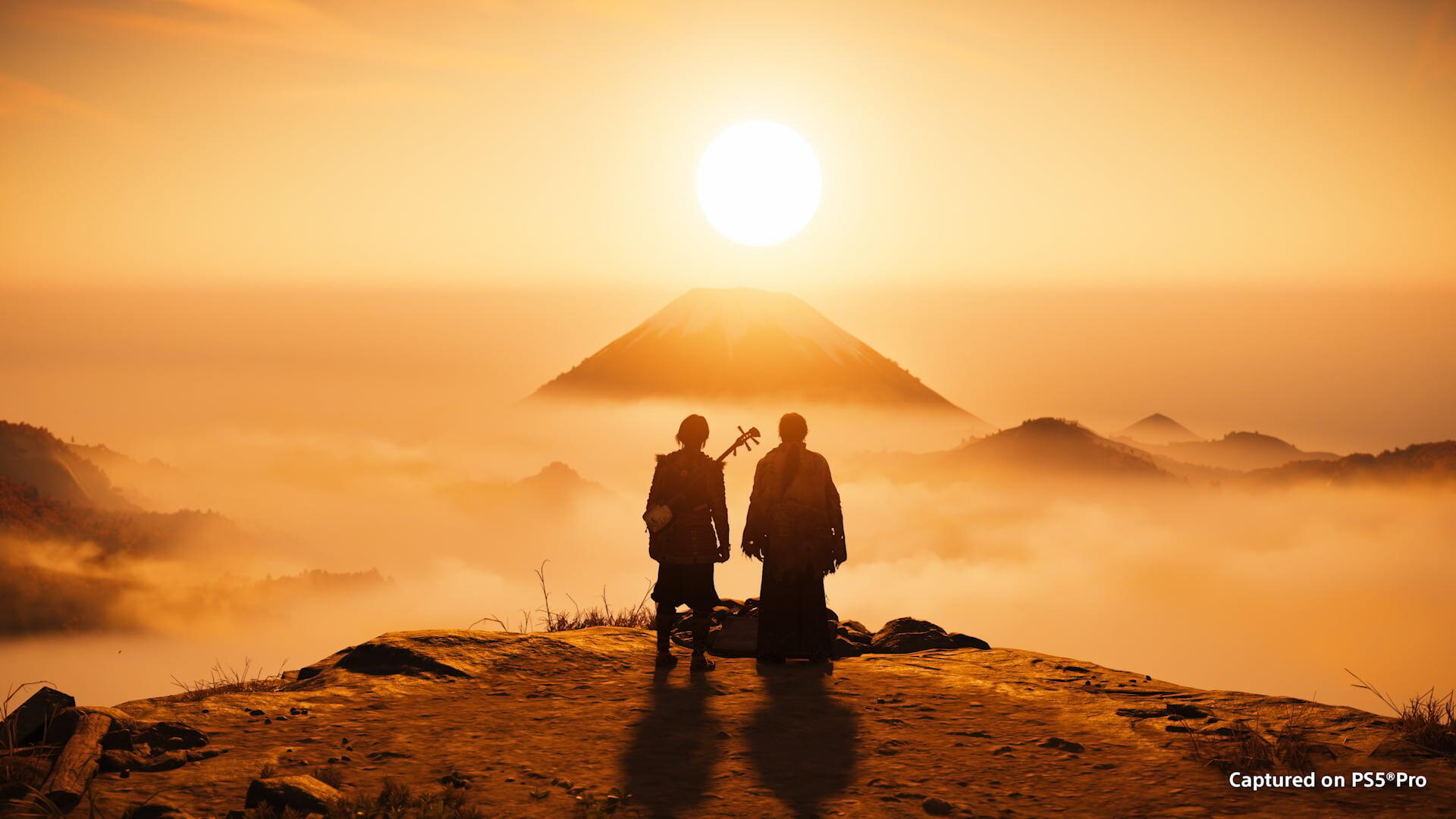 HD PC desktop wallpaper of two silhouetted figures from the video game Ghost of Yōtei on a mountain ridge at sunrise, misty peaks and a pyramid-like Yōtei glowing in golden light.