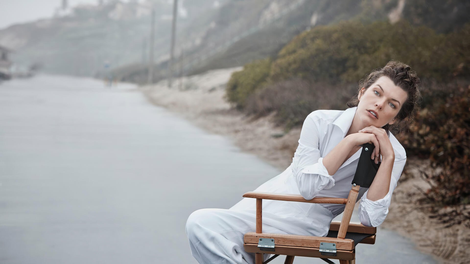 Seated woman in white on a director's chair by a misty shoreline, contemplative portrait — 4K Ultra HD PC desktop wallpaper.