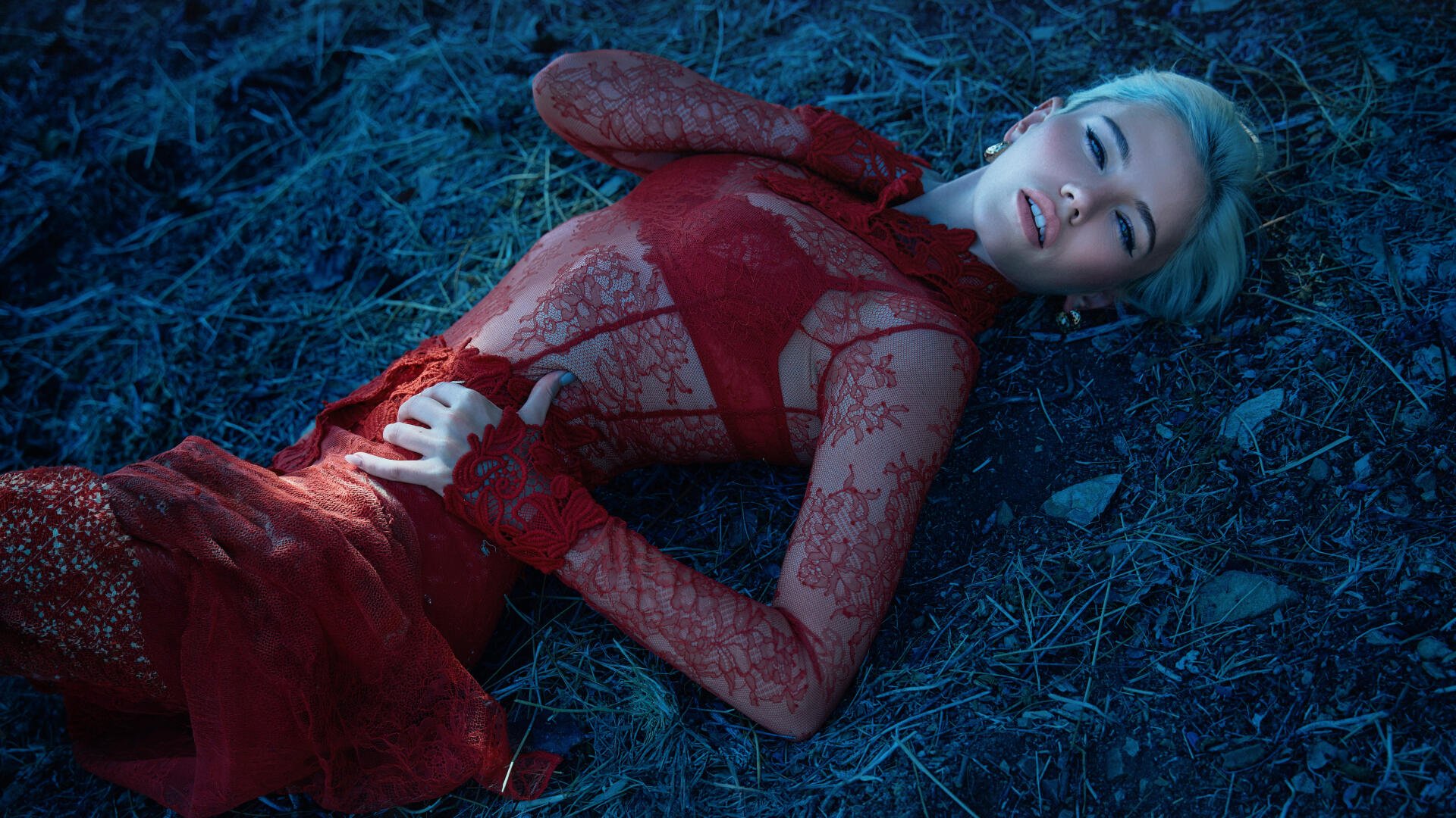 5K Ultra HD PC desktop wallpaper of a music singer in a red lace gown reclining on blue-tinted grass under dramatic lighting.
