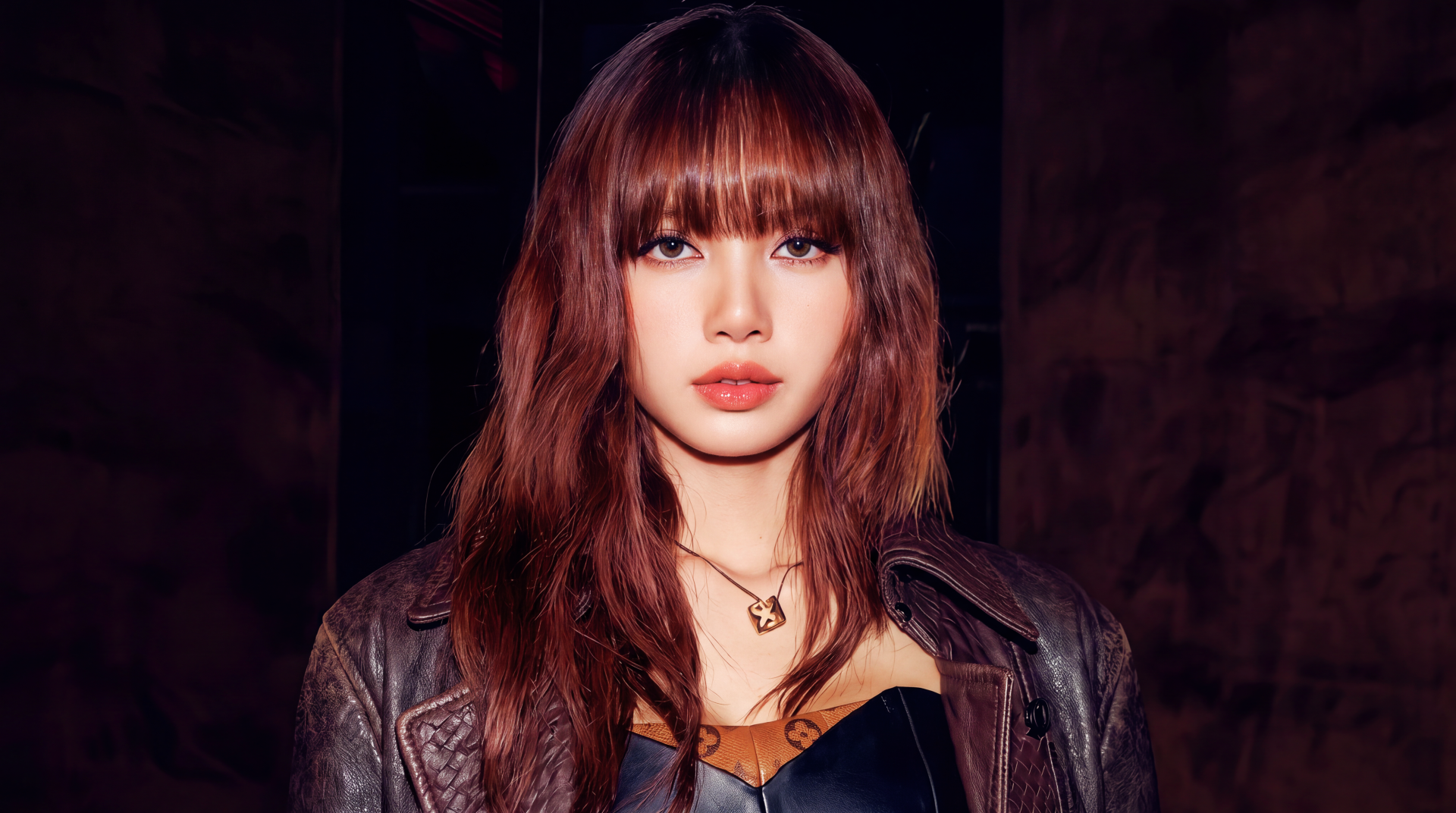 5K desktop wallpaper: close-up portrait of a brunette with bangs in a leather jacket and necklace, K-pop style, moody dark background.