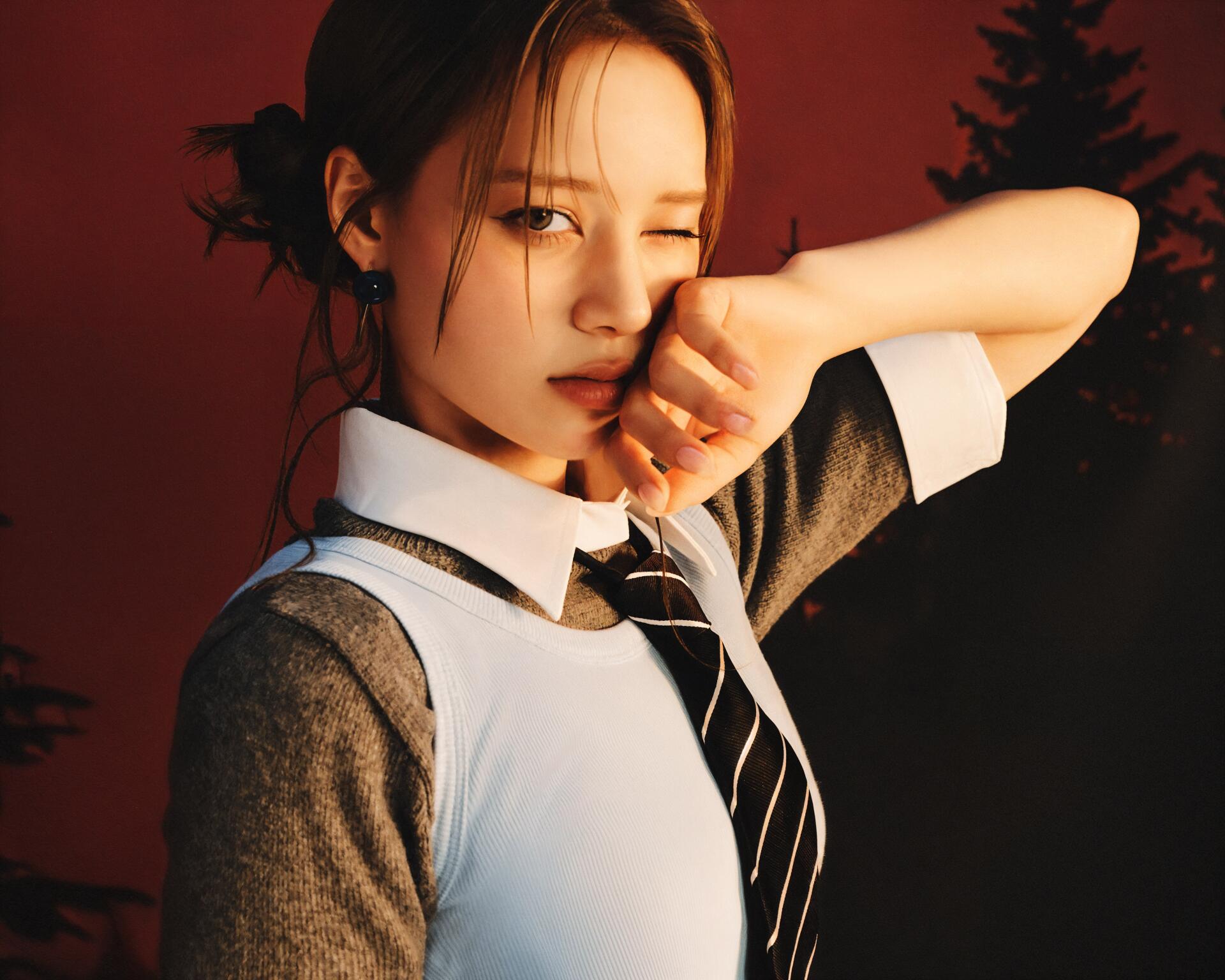 Winking portrait of a woman in a school-style uniform, hand to her mouth, moody Sour Grapes vibe — 4K Ultra HD PC desktop wallpaper/background.