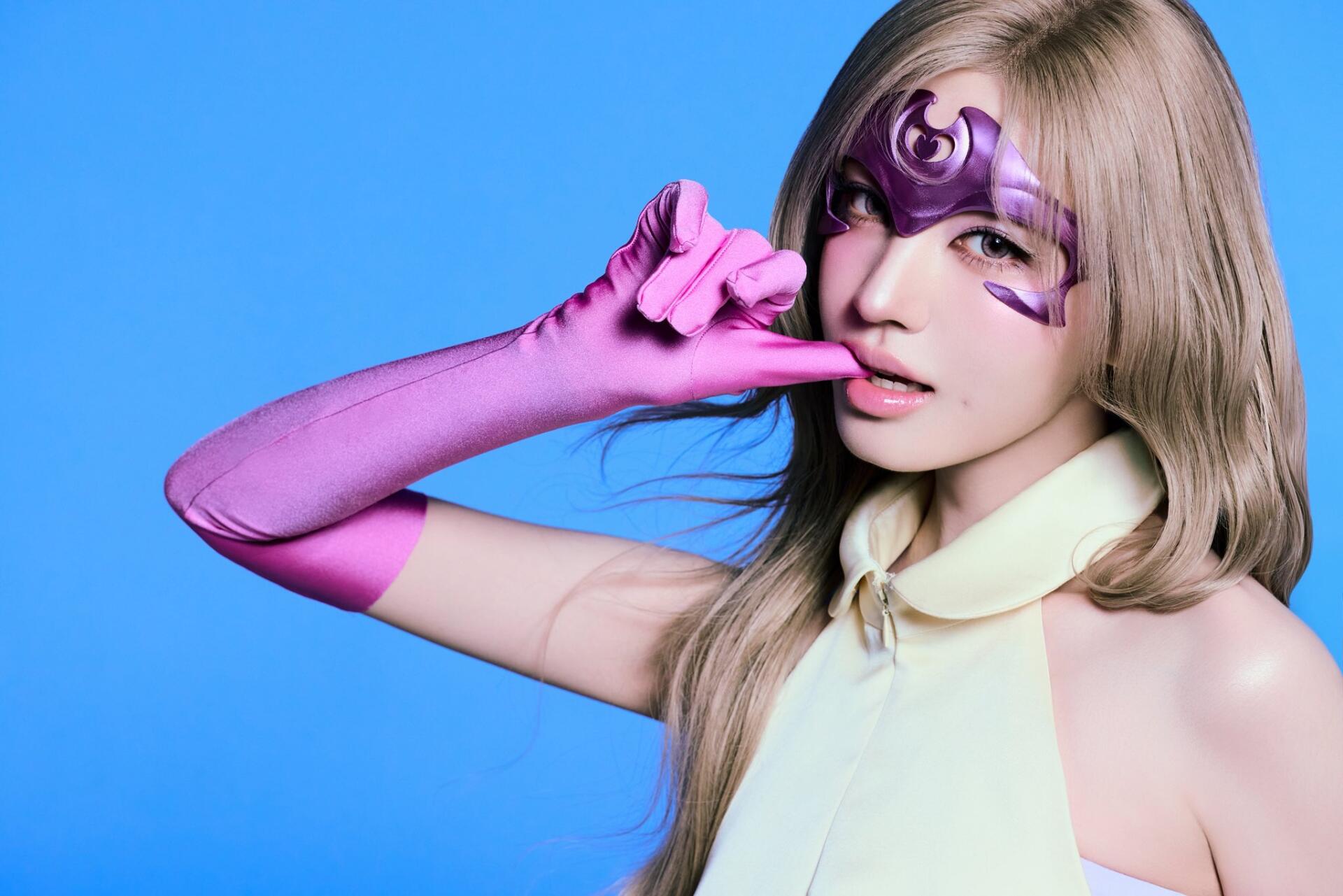 Liz of IVE as a purple-masked superhero in a Looks Can Kill HD desktop wallpaper against a bright blue background.