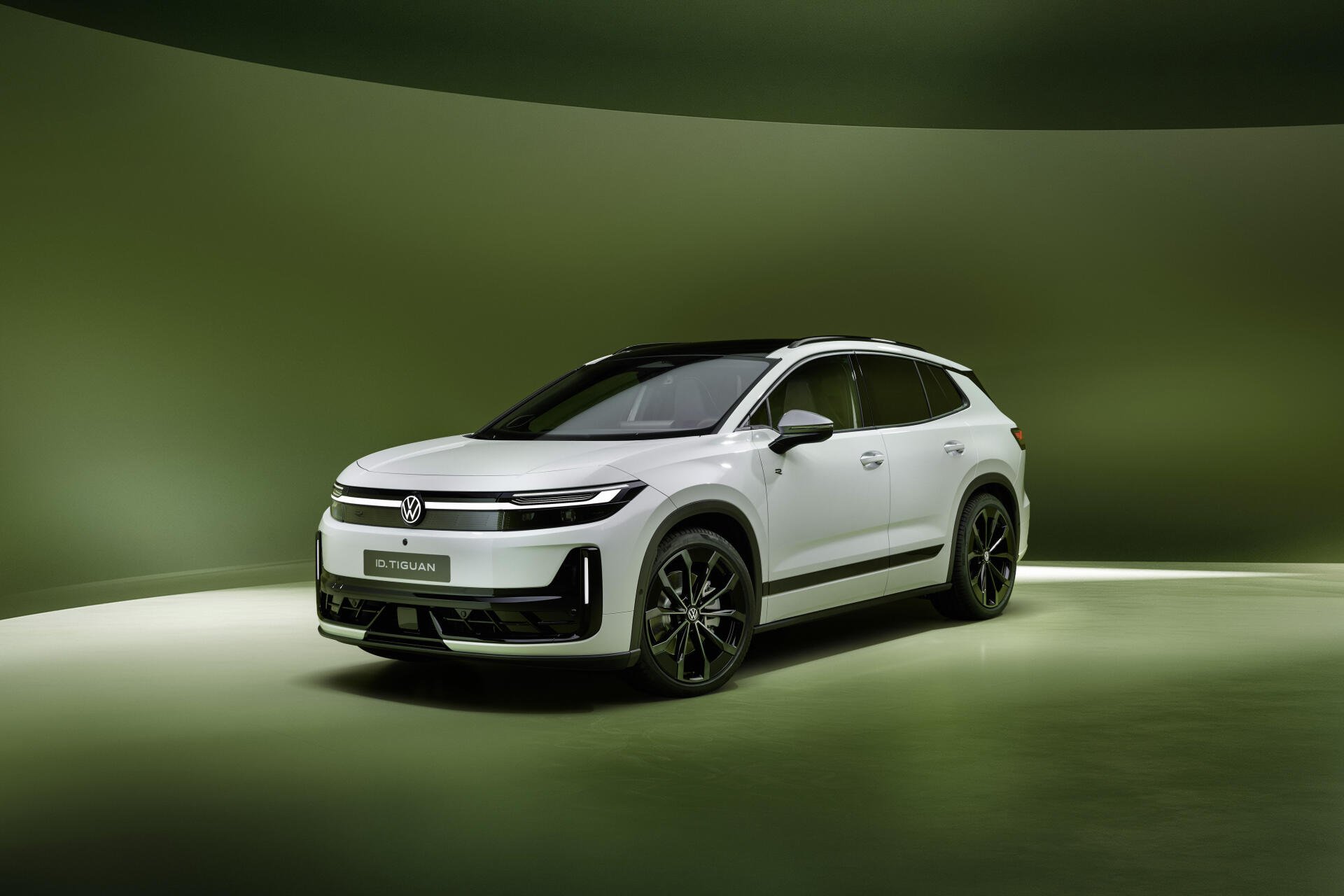 White Volkswagen ID. Tiguan electric SUV on a green studio backdrop, 4K Ultra HD PC desktop wallpaper.