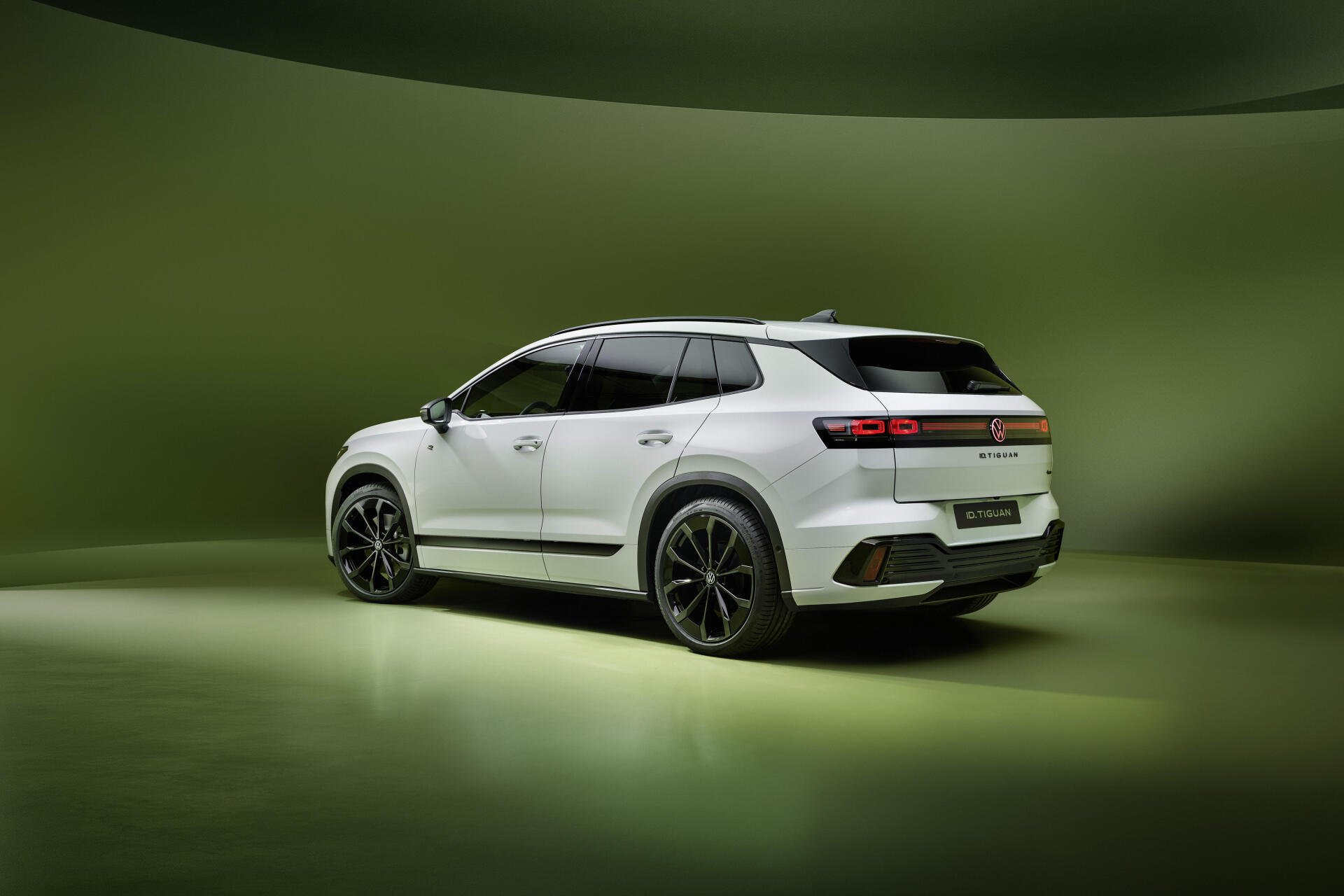 White Volkswagen ID. Tiguan electric SUV in a green studio, featured in a 4K Ultra HD PC desktop wallpaper background.