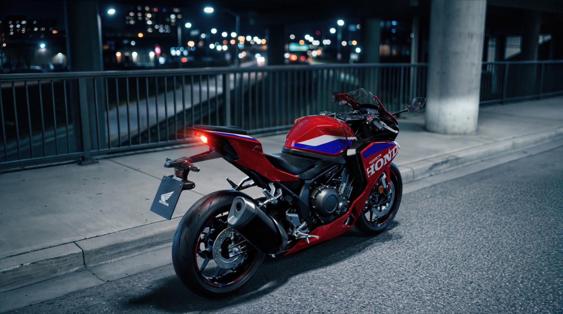 Red Honda CBR500R Four sportbike parked on a city street at night, featured in a 5K Ultra HD desktop wallpaper background.
