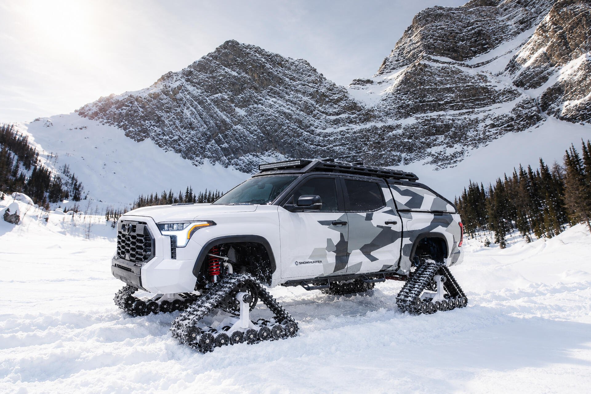 Toyota Tundra Snowhunter with snow tracks in a snowy mountain landscape, 2K Quad HD PC desktop wallpaper and background.