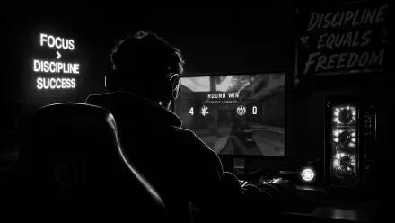 Backlit gamer at a desk playing a shooter, neon FOCUS DISCIPLINE SUCCESS sign and RGB PC tower visible — 4K Ultra HD PC desktop wallpaper/background.