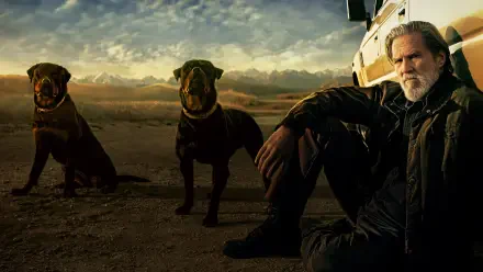 4K Ultra HD PC desktop wallpaper titled The Old Man of a rugged man seated by a vehicle with two dogs in a desert at dusk, moody skies and cinematic, rugged lighting.