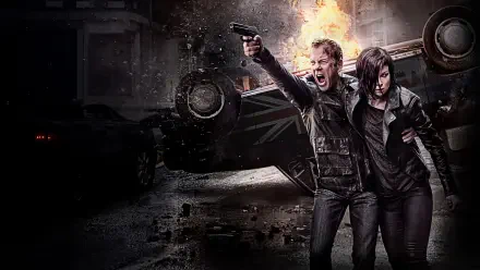 24 action scene 4K Ultra HD PC desktop wallpaper: two gritty, armed protagonists dash past an overturned, burning car amid rain-slicked urban rubble and night-time chaos.