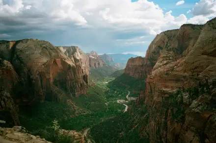 4K Ultra HD PC desktop wallpaper of Zion National Park canyon with towering red-rock mountains, a green valley with trees and a winding river under a partly cloudy sky.