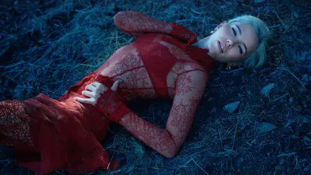 5K Ultra HD PC desktop wallpaper of a music singer in a red lace gown reclining on blue-tinted grass under dramatic lighting.