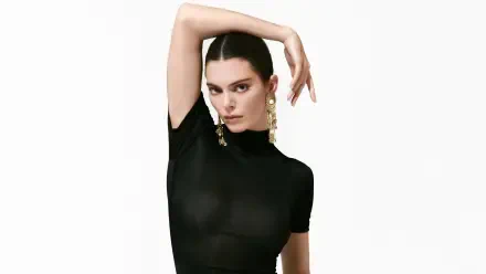 5K Ultra HD desktop wallpaper: fashion portrait of a poised model in a fitted black top, arm raised, wearing bold dangling earrings on a clean white background.