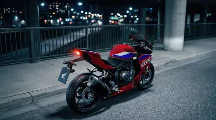 Red Honda CBR500R Four sportbike parked on a city street at night, featured in a 5K Ultra HD desktop wallpaper background.