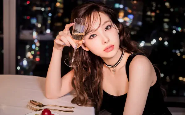 5K Ultra HD wallpaper of a glamorous young woman in K-pop style, holding a champagne flute at a candlelit table with blurred city lights behind her.