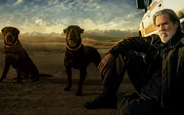 4K Ultra HD PC desktop wallpaper titled The Old Man of a rugged man seated by a vehicle with two dogs in a desert at dusk, moody skies and cinematic, rugged lighting.