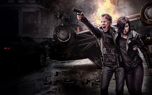 24 action scene 4K Ultra HD PC desktop wallpaper: two gritty, armed protagonists dash past an overturned, burning car amid rain-slicked urban rubble and night-time chaos.