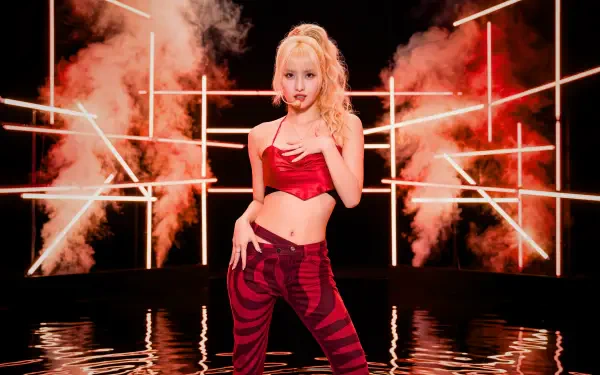 Blonde performer in a red crop top and patterned red pants poses amid neon grid lights and smoke on a reflective stage — K-pop–style 5K desktop wallpaper.