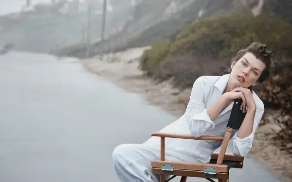 Seated woman in white on a director's chair by a misty shoreline, contemplative portrait — 4K Ultra HD PC desktop wallpaper.