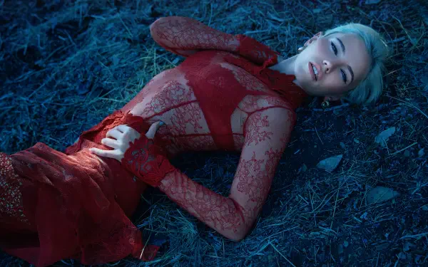 5K Ultra HD PC desktop wallpaper of a music singer in a red lace gown reclining on blue-tinted grass under dramatic lighting.